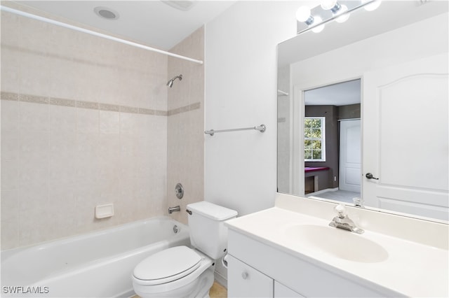 full bathroom with tiled shower / bath, vanity, and toilet