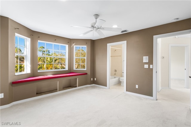 unfurnished bedroom featuring light carpet, ensuite bath, and ceiling fan