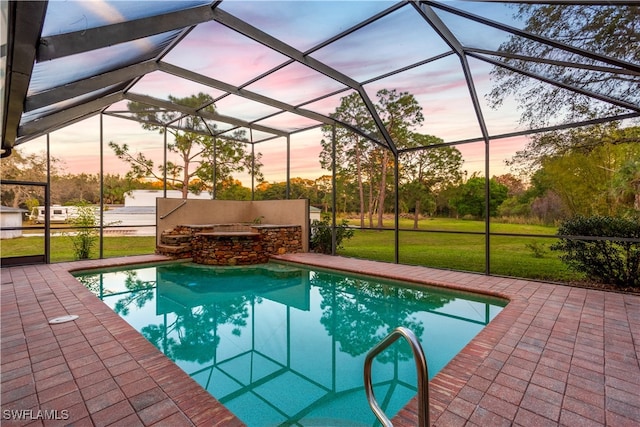 pool at dusk with a lanai, a patio area, and a yard