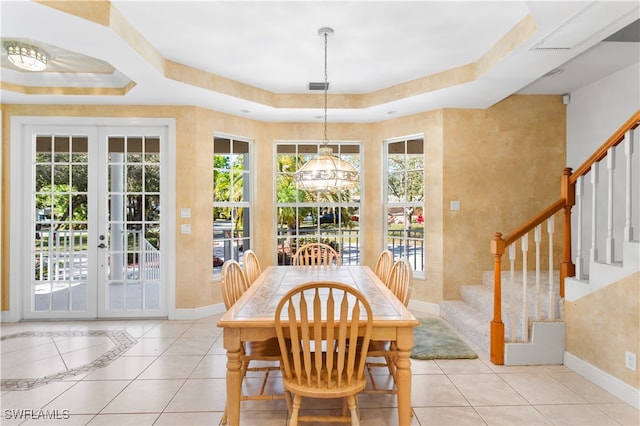 tiled dining space featuring french doors, a tray ceiling, and a wealth of natural light