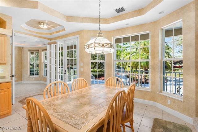 tiled dining room with a raised ceiling, a wealth of natural light, crown molding, and a notable chandelier