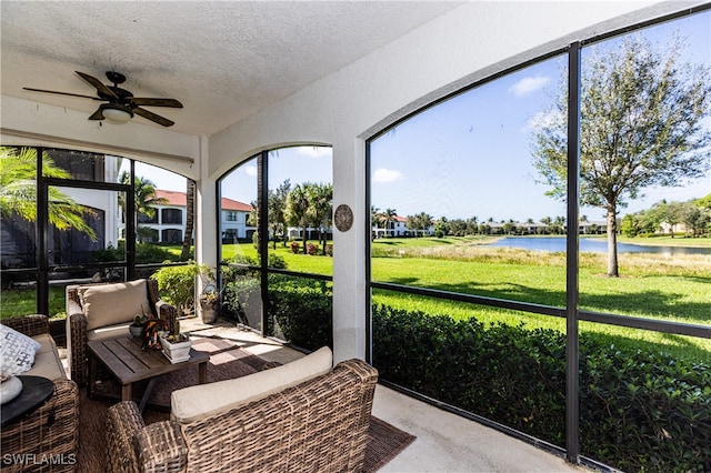 sunroom / solarium featuring ceiling fan and a water view