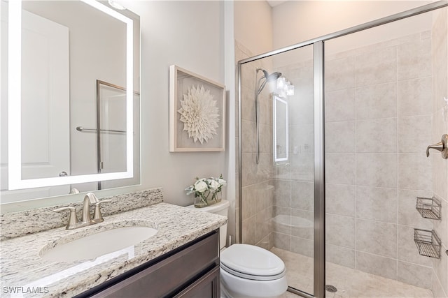 bathroom featuring vanity, an enclosed shower, and toilet