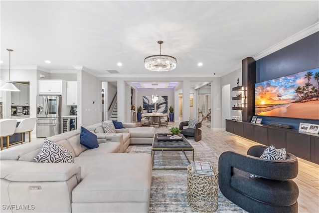 living room with ornamental molding, light hardwood / wood-style floors, and a notable chandelier