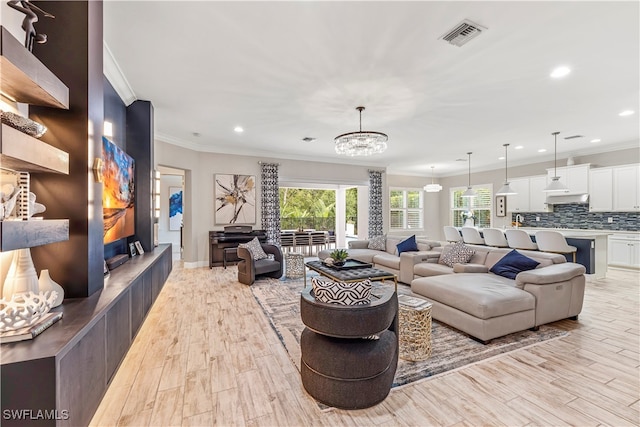 living room featuring crown molding, light hardwood / wood-style floors, and an inviting chandelier