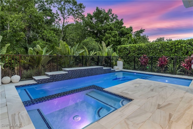 pool at dusk featuring an in ground hot tub