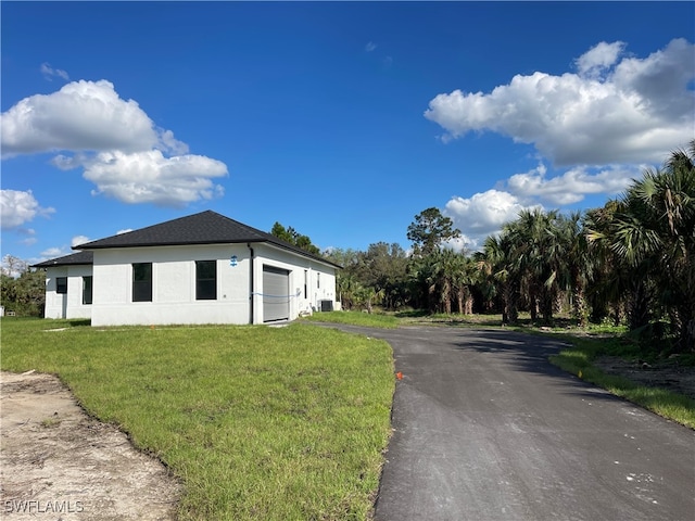 view of side of property with central air condition unit, a garage, and a yard