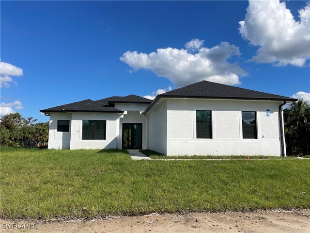 442 4th St SE, Naples, FL 34117 - view of front facade featuring stucco siding, a front yard, and a shingled roof