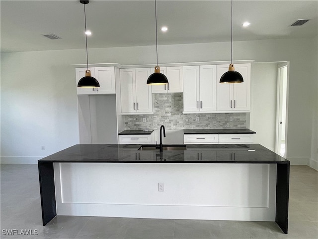 kitchen featuring white cabinets, sink, pendant lighting, and an island with sink