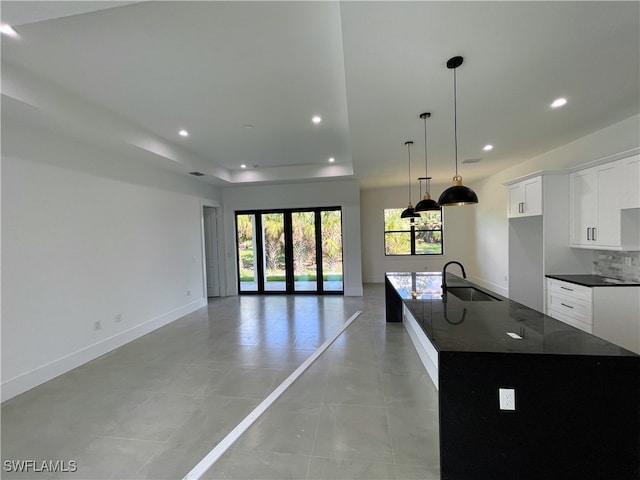 kitchen with sink, dark stone counters, a spacious island, white cabinets, and french doors