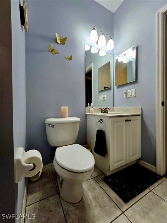 bathroom with toilet, vanity, and tile patterned floors