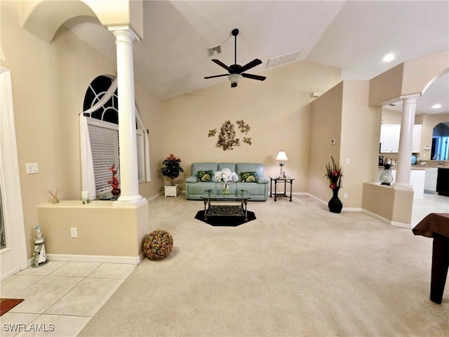 carpeted living room with decorative columns, ceiling fan, and high vaulted ceiling