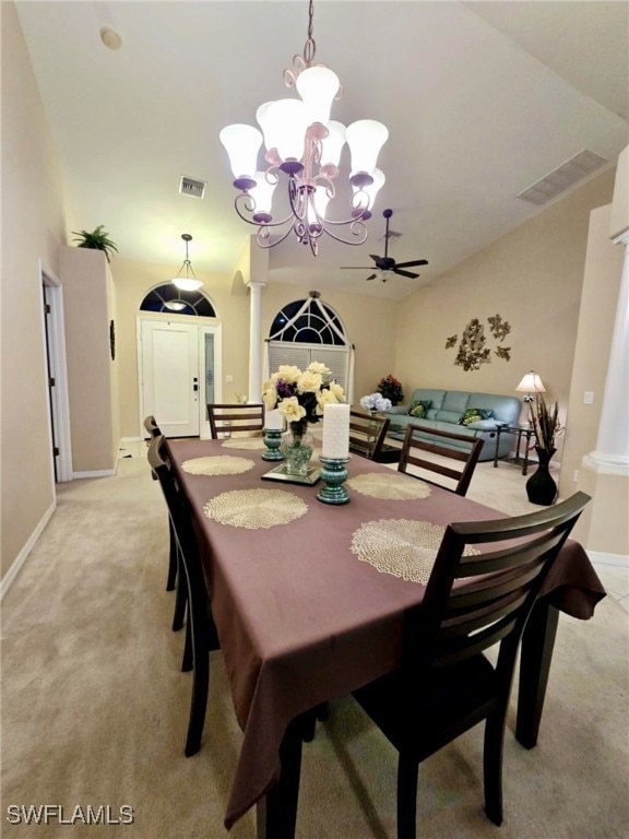 dining space featuring vaulted ceiling, ornate columns, light carpet, and ceiling fan with notable chandelier