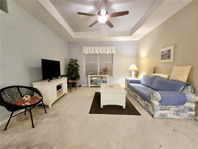 carpeted living room featuring ceiling fan and a tray ceiling