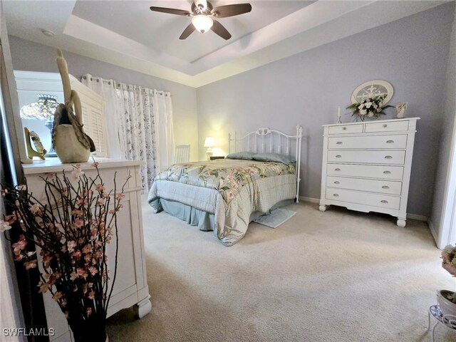 bedroom with carpet floors, a raised ceiling, and ceiling fan