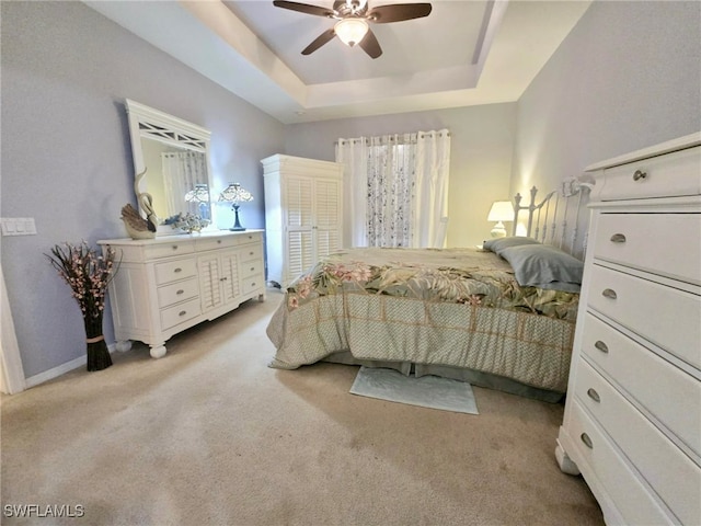 bedroom featuring a raised ceiling, ceiling fan, and light carpet