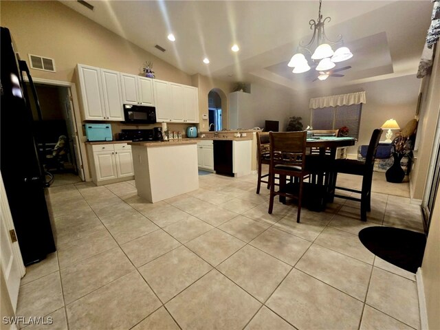 kitchen with white cabinetry, a center island, lofted ceiling, decorative light fixtures, and black appliances