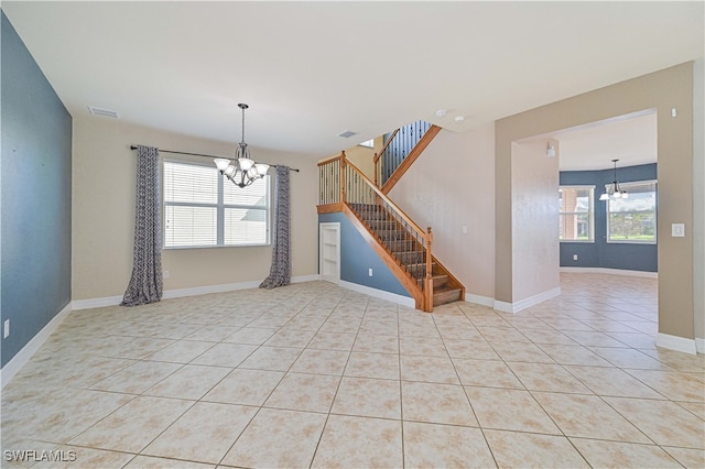 tiled empty room featuring a chandelier