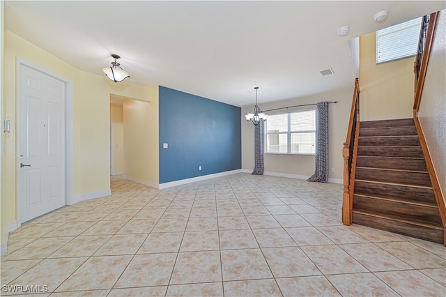 spare room with a chandelier and light tile patterned floors