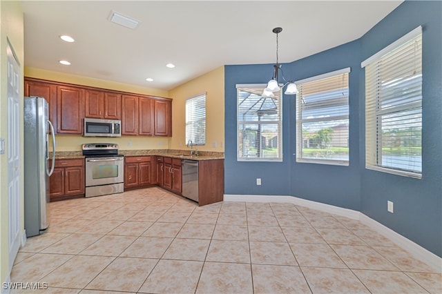 kitchen with light stone countertops, an inviting chandelier, decorative light fixtures, light tile patterned floors, and appliances with stainless steel finishes