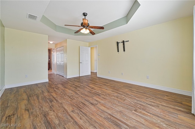 unfurnished room featuring hardwood / wood-style flooring, ceiling fan, and a raised ceiling