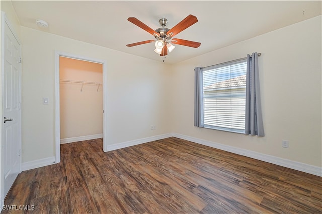 unfurnished bedroom featuring dark hardwood / wood-style flooring, a closet, a spacious closet, and ceiling fan