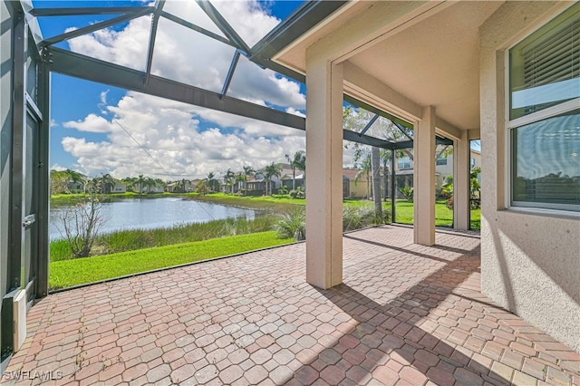 view of patio / terrace featuring a water view and glass enclosure