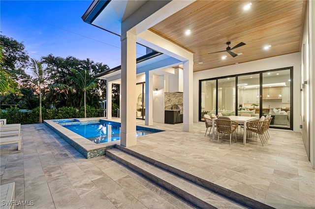 pool at dusk with ceiling fan, a patio, and a hot tub