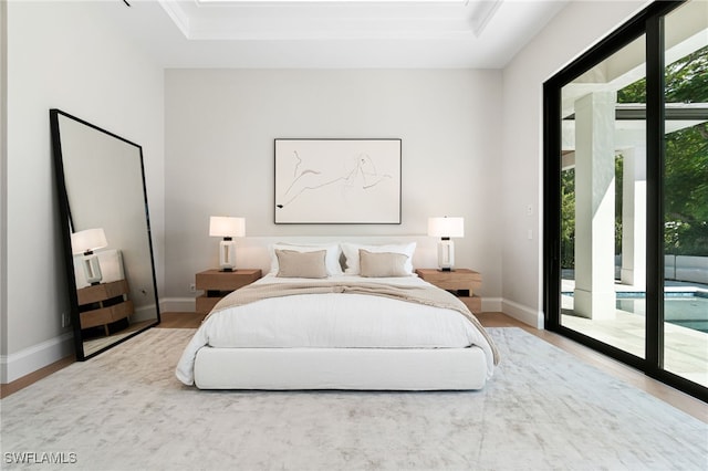 bedroom featuring access to outside, a raised ceiling, and hardwood / wood-style floors