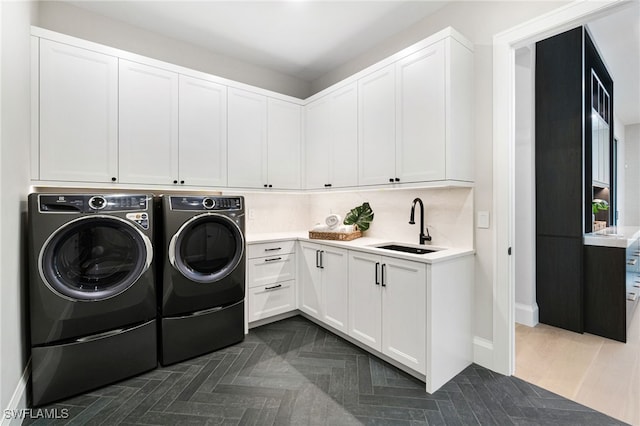 washroom with washer and clothes dryer, dark parquet flooring, sink, and cabinets