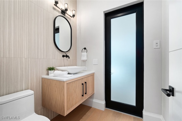 bathroom featuring hardwood / wood-style flooring, vanity, toilet, and tile walls