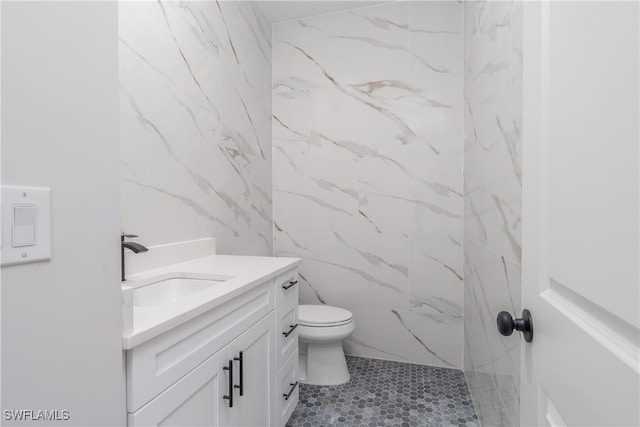 bathroom featuring tile walls, vanity, toilet, and tiled shower