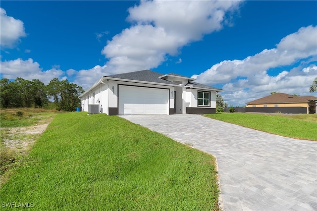 view of front of house with a front lawn, central air condition unit, and a garage