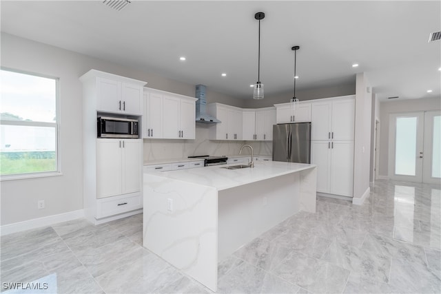 kitchen featuring white cabinetry, appliances with stainless steel finishes, sink, an island with sink, and wall chimney exhaust hood