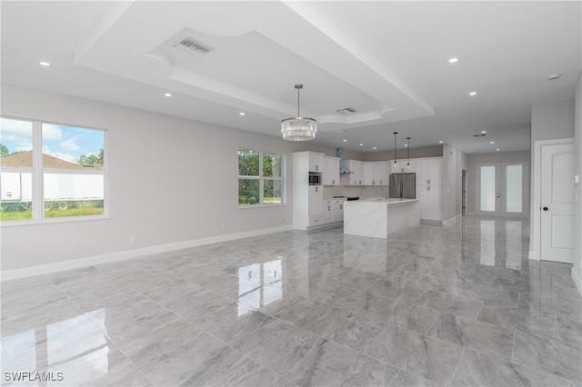 unfurnished living room with french doors, a chandelier, and a raised ceiling