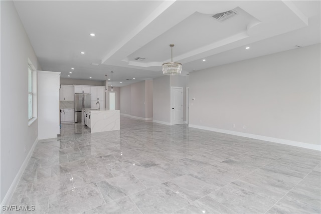 unfurnished living room with sink and a raised ceiling