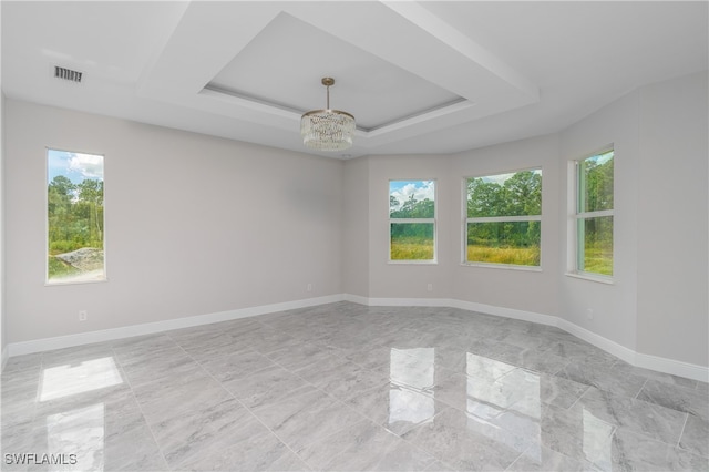 spare room featuring a chandelier and a tray ceiling