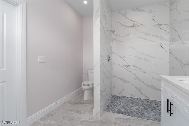 bathroom with vanity, toilet, and tiled shower