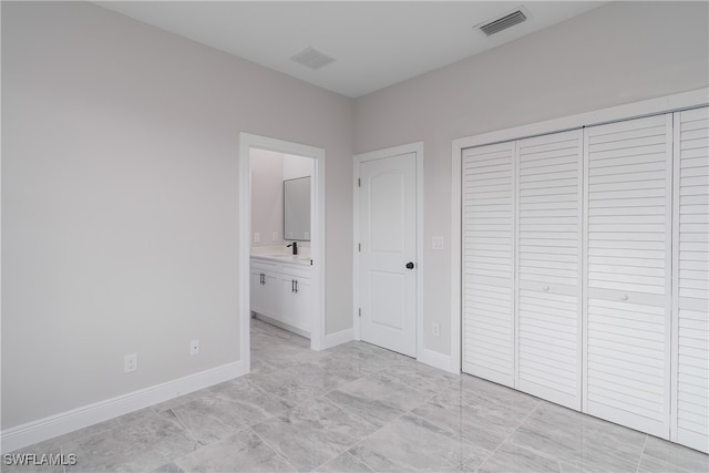 unfurnished bedroom featuring connected bathroom, a closet, and sink