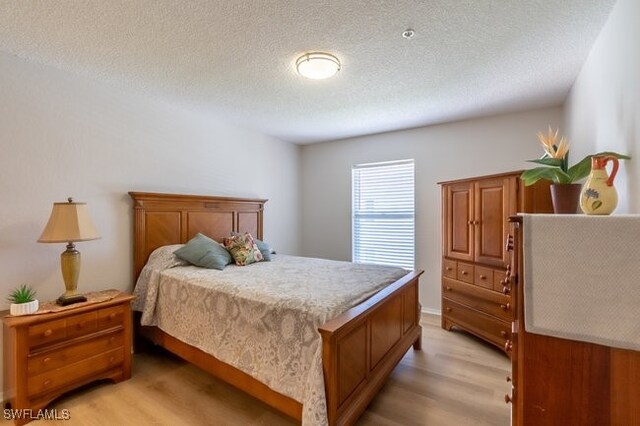 bedroom featuring light wood-type flooring and a textured ceiling