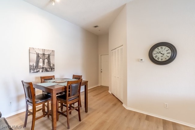 dining space featuring light hardwood / wood-style floors and a high ceiling