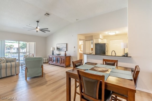 dining area featuring ceiling fan, lofted ceiling, and light wood-type flooring