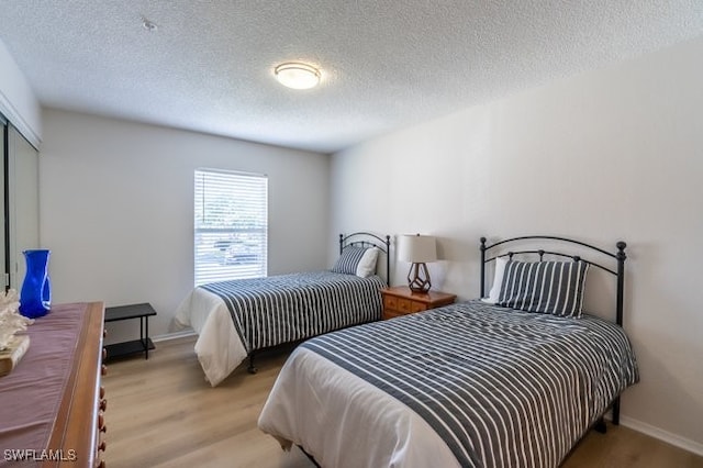 bedroom featuring light hardwood / wood-style flooring and a textured ceiling