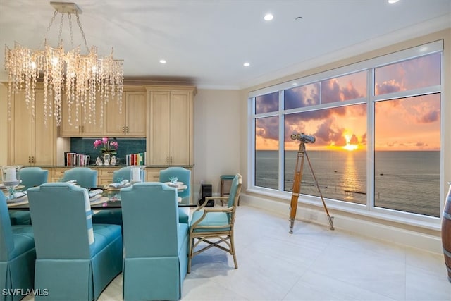 dining room with crown molding, a water view, and a chandelier