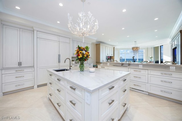 kitchen with decorative light fixtures, light stone countertops, sink, and a large island with sink