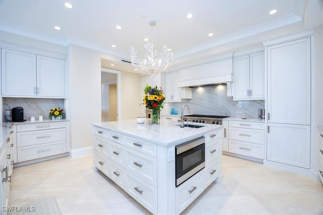 kitchen with tasteful backsplash, stainless steel appliances, a kitchen island with sink, decorative light fixtures, and white cabinets