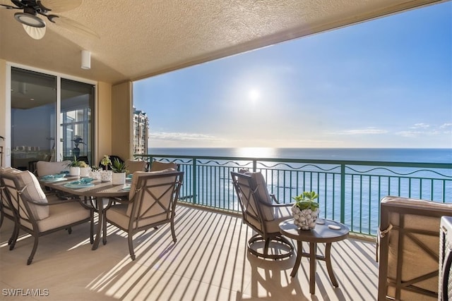 balcony with ceiling fan and a water view