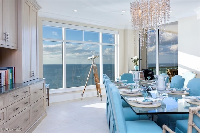 dining room with a water view, ornamental molding, and a notable chandelier