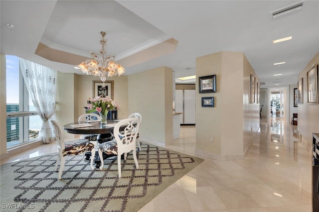 dining area with a raised ceiling, crown molding, and an inviting chandelier