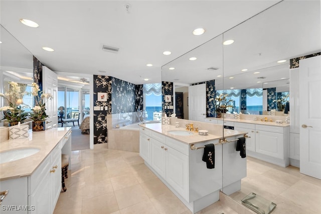 kitchen with light stone countertops, a spacious island, sink, light tile patterned floors, and white cabinets